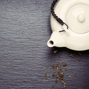 Pouso da Torre - Asia food composition with chinese chopsticks, teapot and dry green tea on a dark stone background, top view, toned, with free space for text