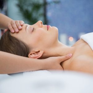 Pouso da Torre - Profile portrait of young Caucasian woman lying on back, keeping her eyes closed while therapist massaging her head and shoulders. Spa concept
